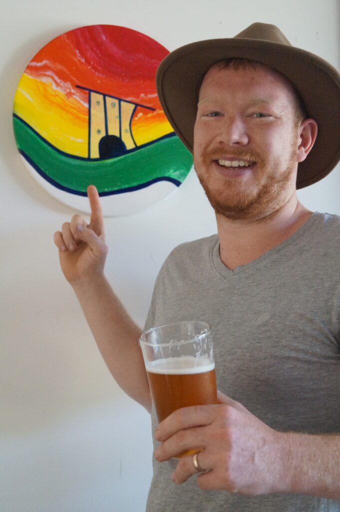Sam with a beer and cubby haus painting