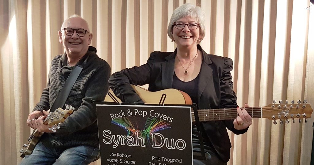 Syrah Duo Joy and Rob holding their guitars and smiling