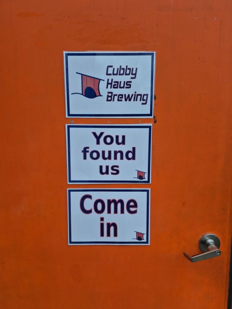 Cubby Haus Brewing orange door with signage "You found us, Come in"