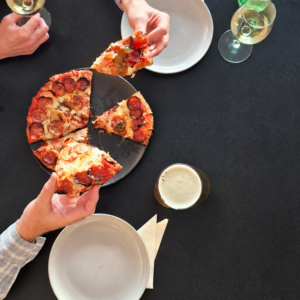 Overhead Pizza Feast with Drinks Hands of a couple sharing pizza with drinks