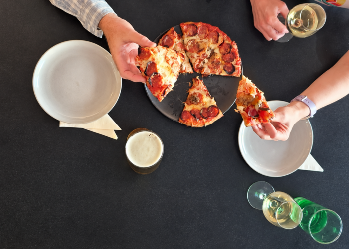 a couple grabbibg slices of pizza